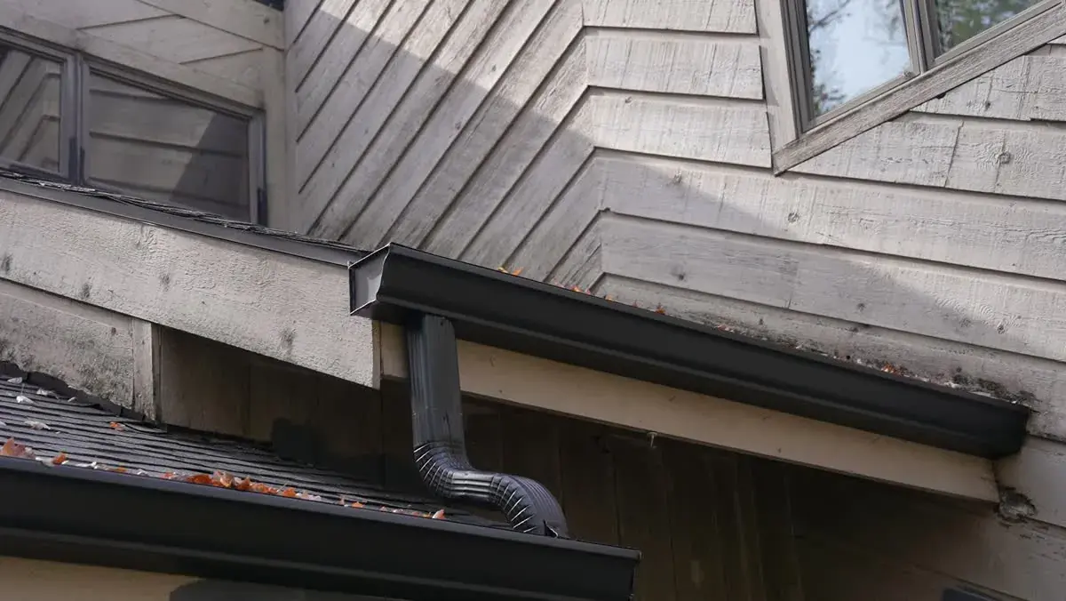 Black seamless gutter and downspout on a wood-sided home
