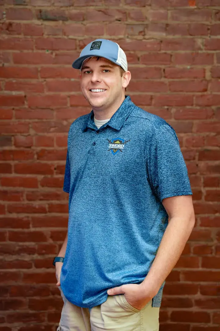 Cory Bryant, co-owner of SWORD Roofing, in a blue SWORD polo and cap