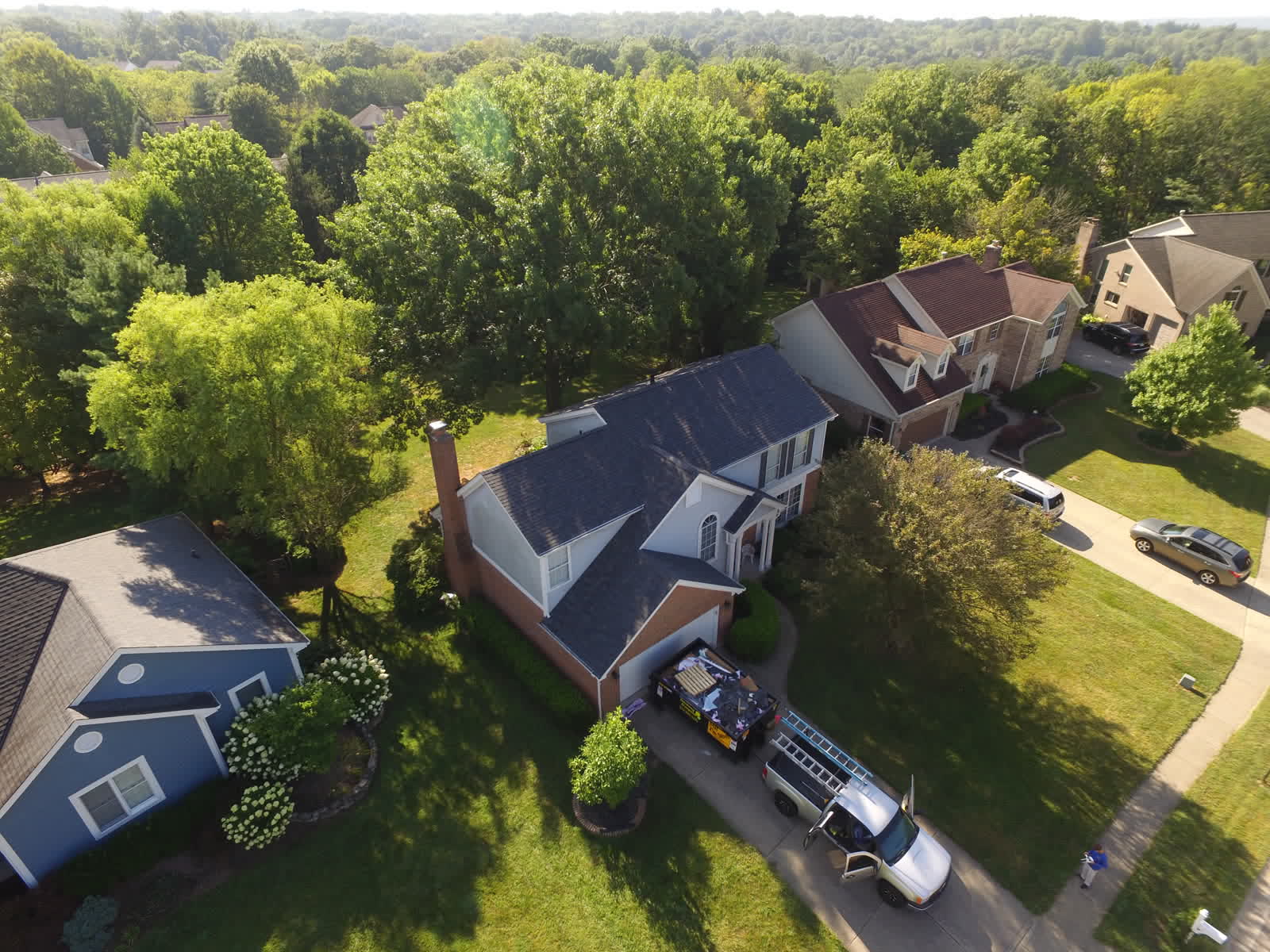Drone photo of a home with a new dark gray shingle roof among trees