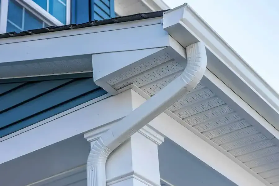 A white gutter and downspout at the corner of a home