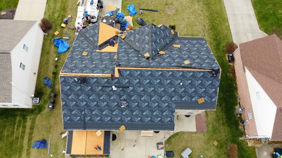 Overhead drone photo of a roof replacement with underlayment down and tarps around the home