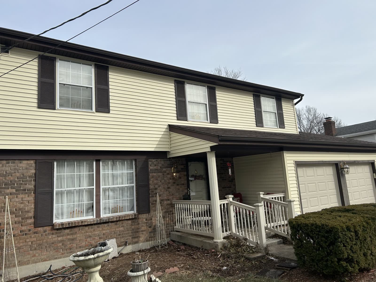 New cream vinyl siding above the brick front and porch of a two-story home