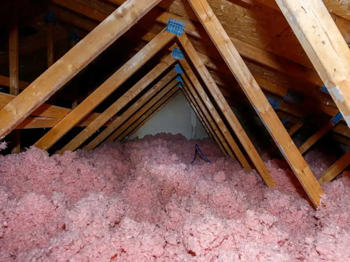 Pink blown-in insulation between the rafters of an attic