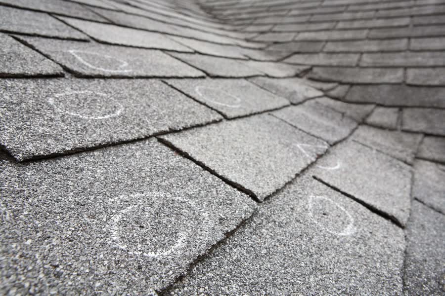 Chalk circles marking damage on gray shingles