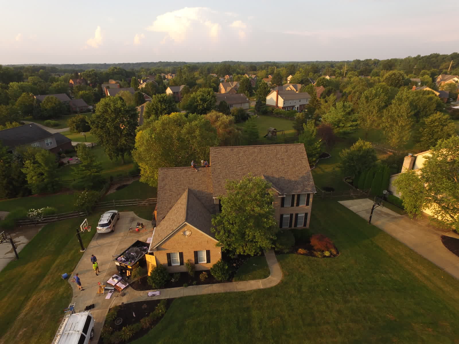 Drone photo of a two-story home with a new shingle roof in a suburban neighborhood