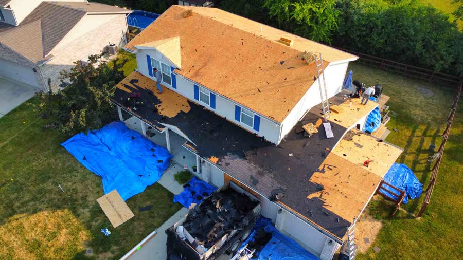 Drone photo of a roof tear-off with tarps covering the yard