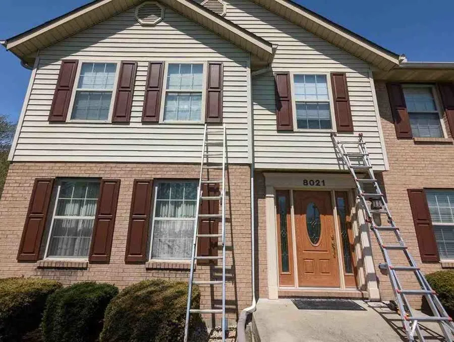 Ladders set against the brick and vinyl front of a two-story home