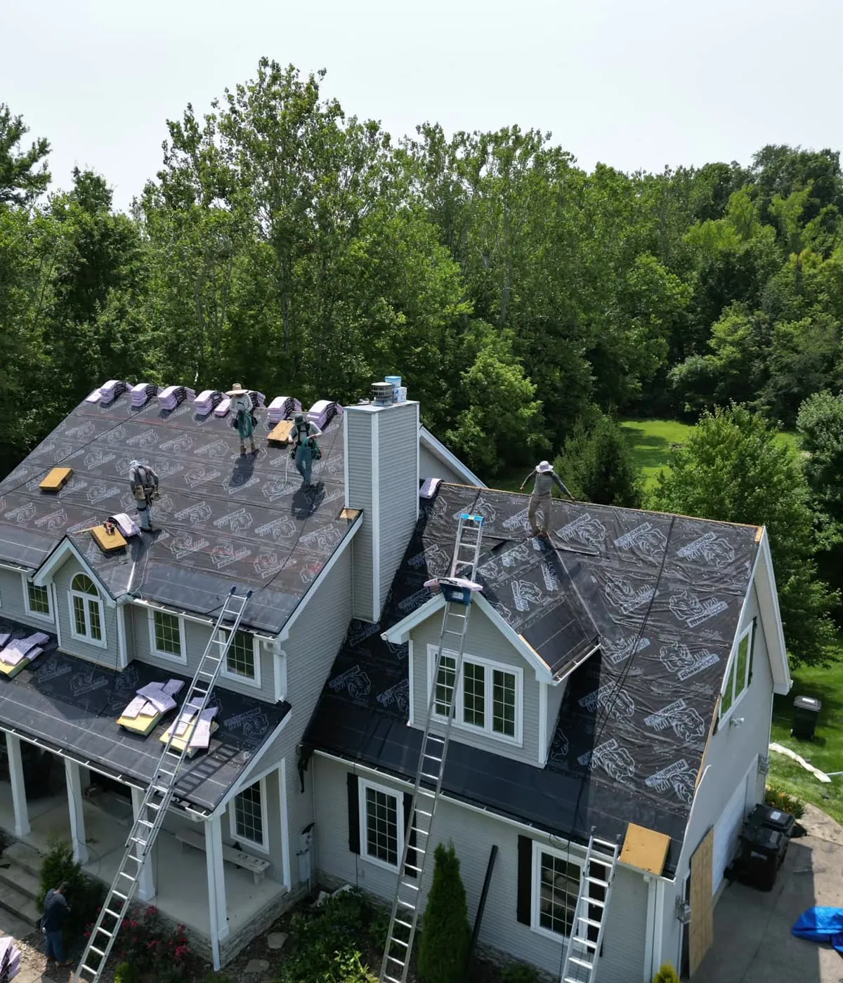 Drone view of a SWORD Roofing crew replacing the shingle roof on a two-story home